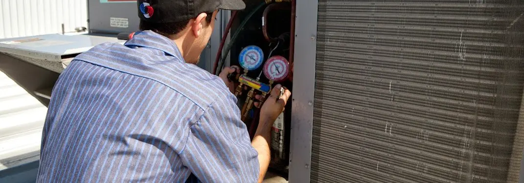 HVAC technician servicing a condenser unit in Cheval