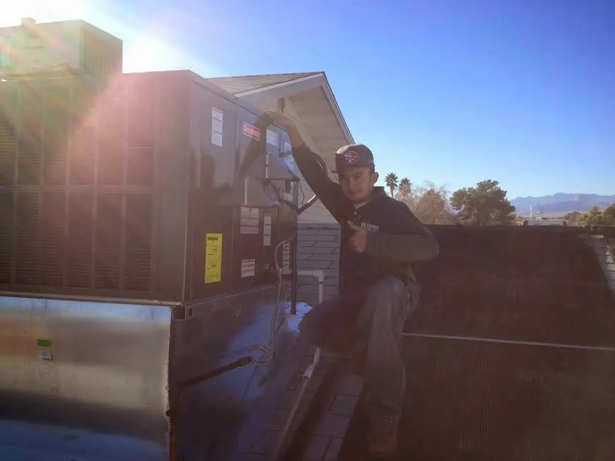 HVAC technician performing Air Duct Cleaning on a rooftop unit in Cheval